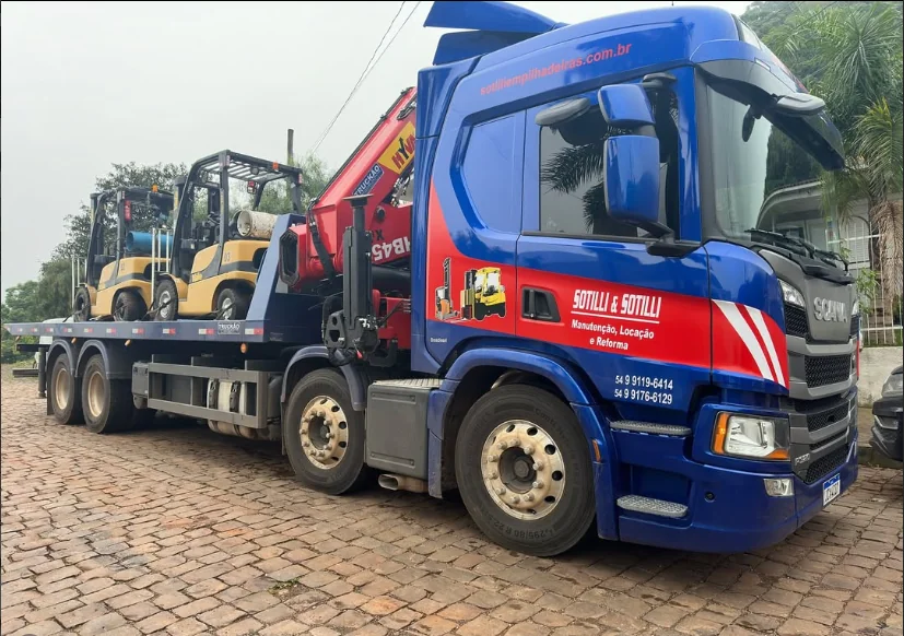 Caminhão azul da Sotilli transportando duas empilhadeiras na plataforma